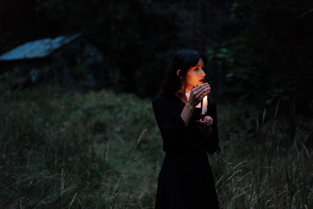 woman holding candle in dark forest
